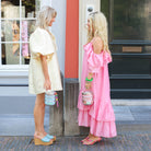 Two women holding Boho-Tiffin stainless steel lunchboxes with playful prints while standing on a city street.